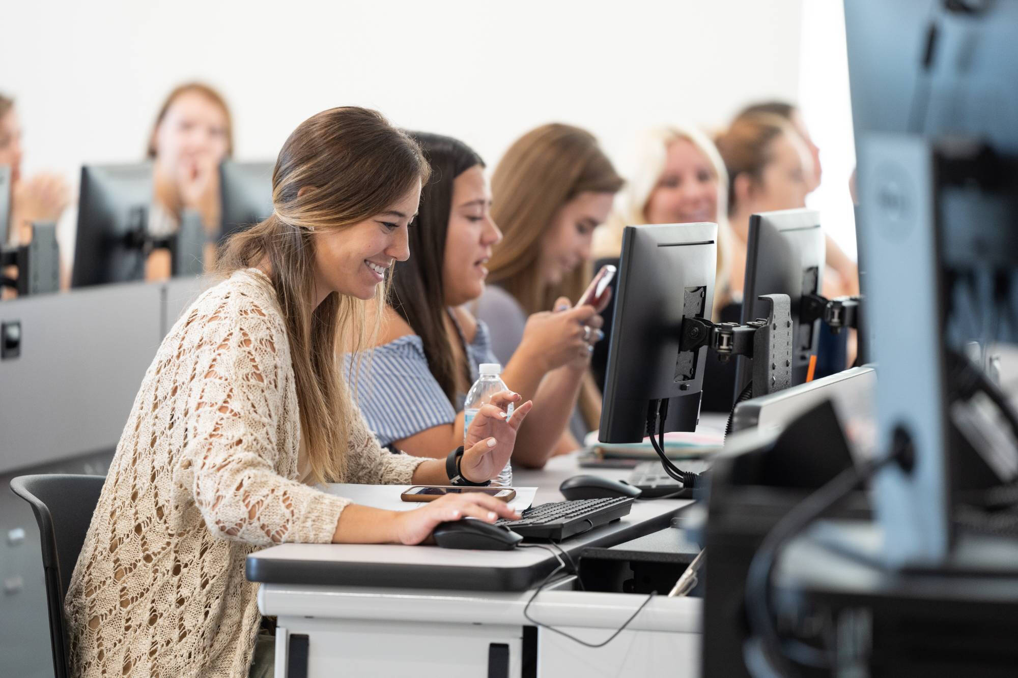 Women sit in a classroom in front of computer screens